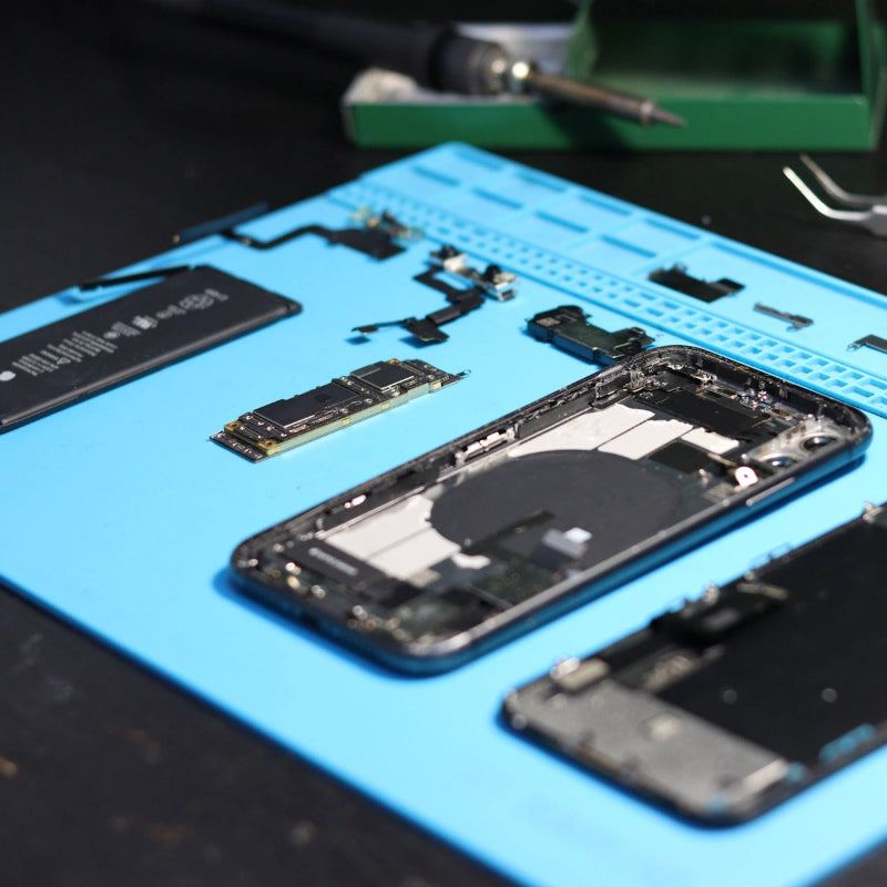 Disassembled iPhone with battery, logic board and parts laid out on a repair mat at Regen Computers Hamilton